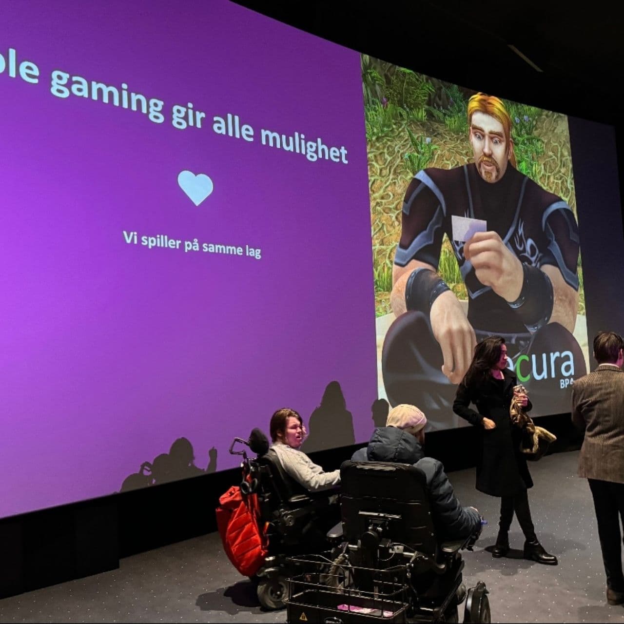 Presentasjon om inkluderende gaming med tekst og digital figur på skjerm – et sterkt bilde på tilgjengelighet og digitalt fellesskap.