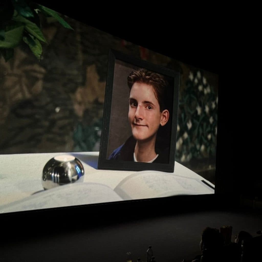 Kinolerret med portrett, bok og metallgjenstand – sett fra salen med publikum i forgrunnen. Et bilde på felles minne og ettertanke.