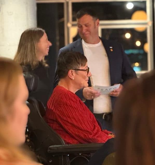 Person i rullestol i samtale med andre deltakere under et arrangement, omgitt av moderne interiør og store vinduer – et bilde på dialog, mangfold og deltakelse.